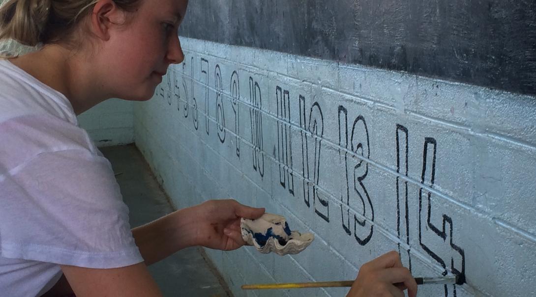 A Projects Abroad volunteer paints a classroom in Samoa A volunteer works with children in Samoa on their education